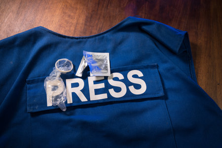 Media Journalism fake news concept. Blue journalist (press) vest in dark with backlight and fog. Dirty money on journalist vest. Selective focusの写真素材