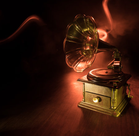 Music concept. Old gramophone on a dark background. Retro gramophone with disc on wooden table with toned backlight. Selective focusの写真素材