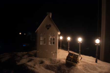 Little decorative cute small houses in snow at night in winter, Christmas and New Year miniature house in the snow at night with fir tree. Holiday concept. Selective focusの写真素材