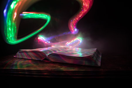 A stack of old books. Vintage book on wooden table. Magic lightning around a glowing book in the room of darkness. Selective focusの写真素材