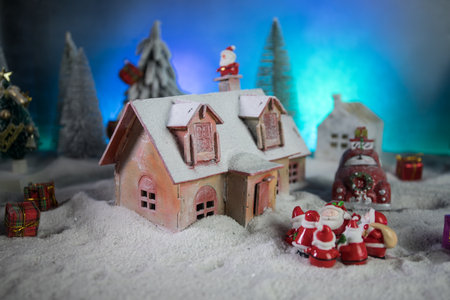 Christmas and New Year holidays concept. Little decorative cute small houses in snow at night. Traditional holiday attributes on snow. Creative artwork decorations. Empty space for your textの写真素材