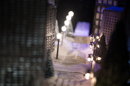 Little miniature city with road and lights. Decorative cute small houses in snow at night in winter. Creative Holiday concept. Christmas and New Year attributes decorated composition.の写真素材