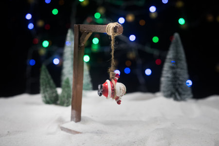 Funny New Year concept. Santa claus figurine is hanged upside down on scaffold. Creative artwork...