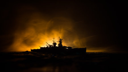 War concept. Night battle scene at sea. Dramatic toned clouds effect. Silhouette of the battle ship in night. Miniature creative table decoration. Selective focusの写真素材