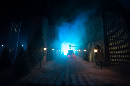 Little miniature city with road and lights. Decorative cute small houses in snow at night in winter. Creative Holiday concept. Christmas and New Year attributes decorated composition.の写真素材