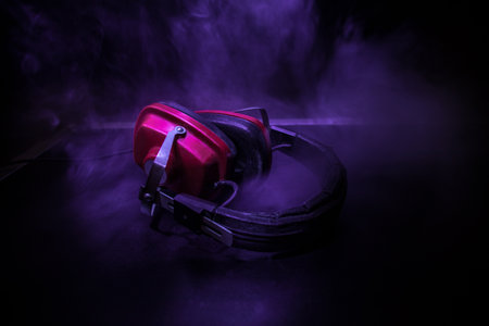Dj music club concept. Close up old vintage headphones on dark background with colorful light. Selective focusの写真素材