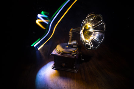 Music concept. Old gramophone on a dark background. Retro gramophone with disc on wooden table with toned backlight. Selective focusの写真素材