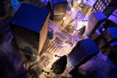 Little miniature city with road and lights. Decorative cute small houses in snow at night in winter. Creative Holiday concept. Christmas and New Year attributes decorated composition.の写真素材