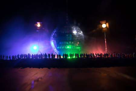 Clublife creative concept. Crowd miniature standing at big disco mirror ball with lights. Night club...