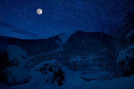 Mountain Road through the snowy forest on a full moon night. Scenic night winter landscape of dark blue sky with moon and stars. Azerbaijanの写真素材