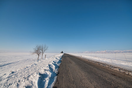 Countryside road through winter field covered in snow. Clear asphalt road. Azerbaijan