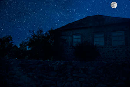 Old house with a Ghost in the forest at misty night or Night scene with House under moon. Old mystic building in dead tree forest.の写真素材