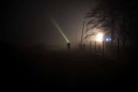 Silhouette of person standing in the dark forest with light. Horror halloween concept. strange silhouette in a dark spooky villageの写真素材