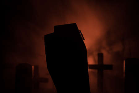 Creative artwork. Miniature wooden coffin with zombie inside. Scary view of zombies at cemetery. Horror Halloween concept. Selective focusの写真素材