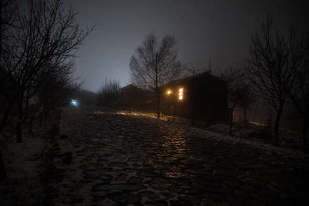Wooden house in winter forest. Mountain house in the snow at night. Misty night. Long exposure shotの写真素材