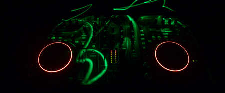 Club music concept. DJ console deejay-mixing desk in dark with colorful light. Mixer equipment...