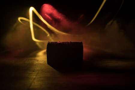 A dark wooden treasure chest with lid closed on wooden table. Selective focus