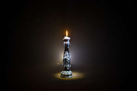 Single burning candle. Light of flame and flowing candle wax, dark background. Selective focus