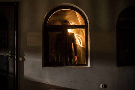 Silhouette of an unknown shadow figure on a door through a closed glass door. The silhouette of a...
