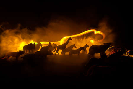 A group of animals are grouped together at foggy night with burning colorful background. Animals Running Escaping to Save Their Lives from fire. Selective focus.の写真素材