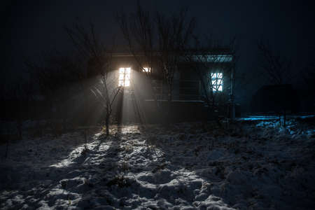 Wooden house in winter forest. Mountain house in the snow at night. Misty night. Long exposure shot