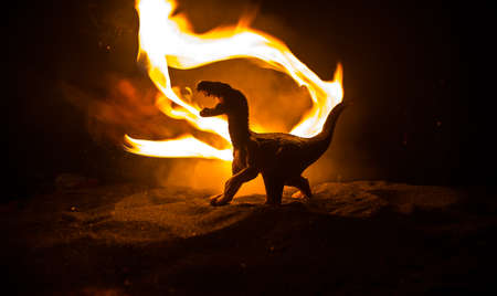 Silhouette of giant Dinosaur in foggy night. Creative decoration with little miniature. Burning misty background. Selective focusの写真素材