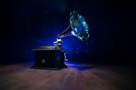 Music concept. Old gramophone on a dark background. Retro gramophone with disc on wooden table with toned backlight. Selective focusの写真素材
