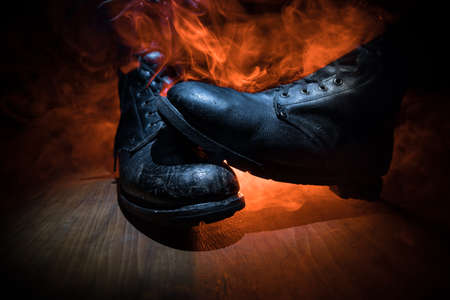 War concept. Old military shoe in a dark toned foggy background. Creative concept of conflict between countries, military aggression. Selective focusの写真素材