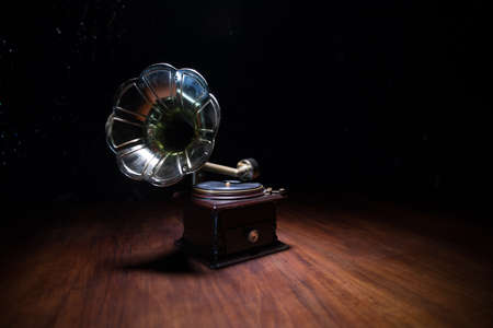 Music concept. Old gramophone on a dark background. Retro gramophone with disc on wooden table with toned backlight. Selective focusの写真素材