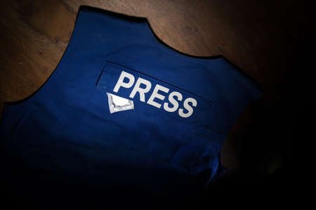 Media Journalism fake news concept. Blue journalist (press) vest in dark with backlight and fog. Dirty money on journalist vest. Selective focusの写真素材