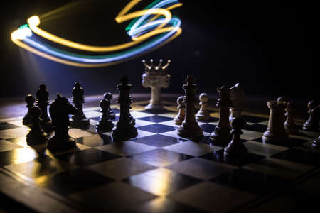 Beautiful crown miniature on chessboard. chess board game concept of business ideas and competition and strategy ideas concept. Chess figures on a dark background with smoke and fog. Selective focusの写真素材