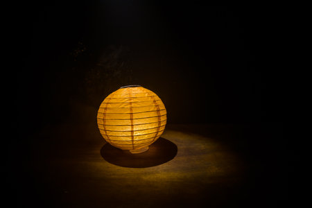 Beautiful paper lantern glowing on wooden table in dark. Selective focusの写真素材