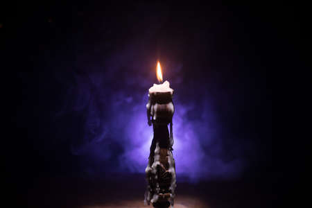 Single burning candle. Light of flame and flowing candle wax, dark background. Selective focusの写真素材