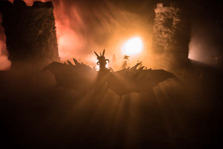 Fantasy battle scene with dragons attacking a medieval castle at night. Battle between dragon and heroic soldiers. Creative table decoration. Selective focusの写真素材