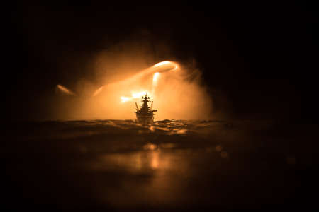 War concept. Night battle scene at sea. Dramatic toned clouds effect. Silhouette of the battle ship in night. Miniature creative table decoration. Selective focusの写真素材