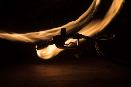 Creative concept. Silhouette of gasoline pistol miniature on dark toned foggy background. Fuel gun...