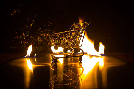 Empty shopping trolley on dark toned foggy background with some copy space. Financial crisis...