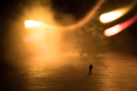 virus global pandemic concept. Miniature man standing near big virus novel in dark. Creative decoration with fog and backlight. Selective focusの写真素材