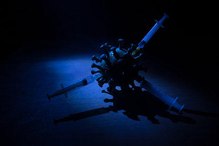 Vaccine concept with syringe and green novel miniature. Vaccine Concept of fight against coronavirus. Creative decoration with fog and backlight. Selective focusの写真素材