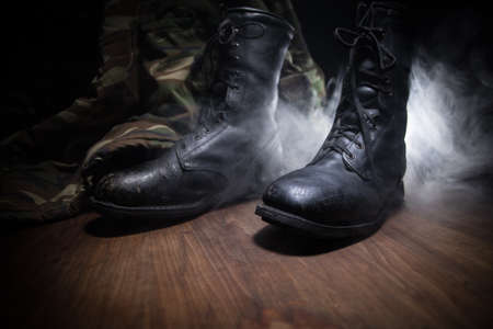 War concept. Old military shoe in a dark toned foggy background. Creative concept of military...