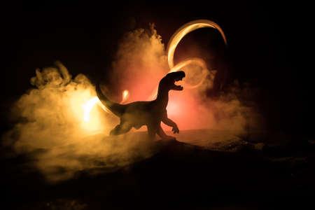 Silhouette of giant Dinosaur in foggy night. Creative decoration with little miniature. Burning misty background. Selective focusの写真素材