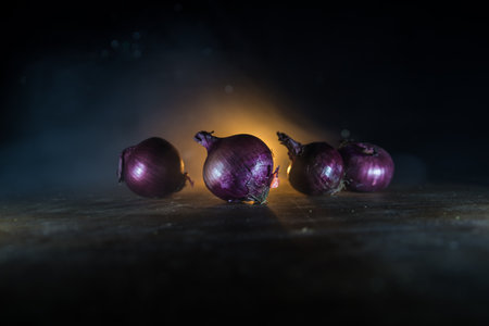Vegetable concept. Purple onions on wood in dark. Selective focus. Colorful background.の写真素材