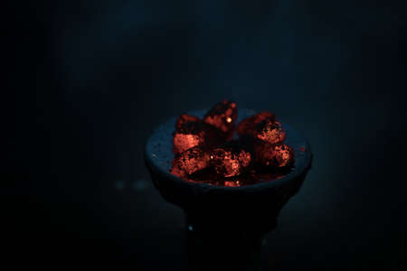 Close-up of burning charcoal cubes. Action. Cubes of embers burning in bowl for smoking hookah. Creative artwork decoration on dark background. Empty space. Selective focusの写真素材