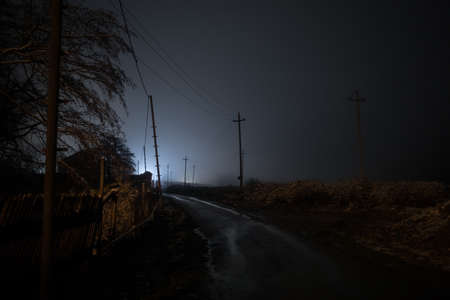 Night street country road with buildings and fences covered in fog lamp. Or Mysterious night in Azerbaijan mountain village. Long exposure shotの写真素材