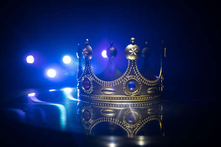 low key image of beautiful queen / king crown over wooden table. vintage filtered. fantasy medieval period. Selective focus. Colorful backlightの写真素材