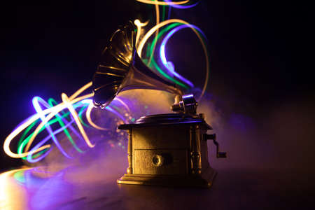 Music concept. Old gramophone on a dark background. Retro gramophone with disc on wooden table with toned backlight. Selective focusの写真素材