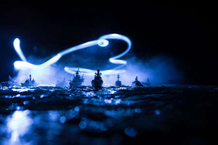 War concept. Night battle scene at sea. Dramatic toned clouds effect. Silhouette of the battle ship in night. Miniature creative table decoration. Selective focusの写真素材