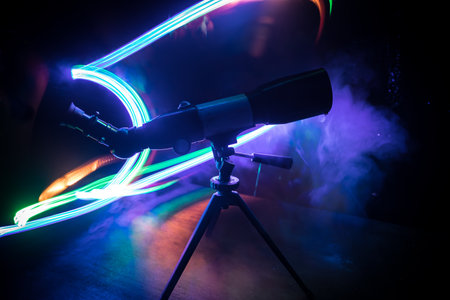 Silhouette of a astronomy telescope on dark foggy backlight. Selective focus