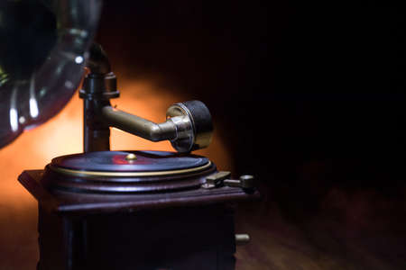 Music concept. Old gramophone on a dark background. Retro gramophone with disc on wooden table with toned backlight. Selective focusの写真素材