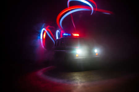 Police car chasing a car at night with fog background. 911 Emergency response police car speeding to scene of crime. Creative decoration. Selective focusの写真素材